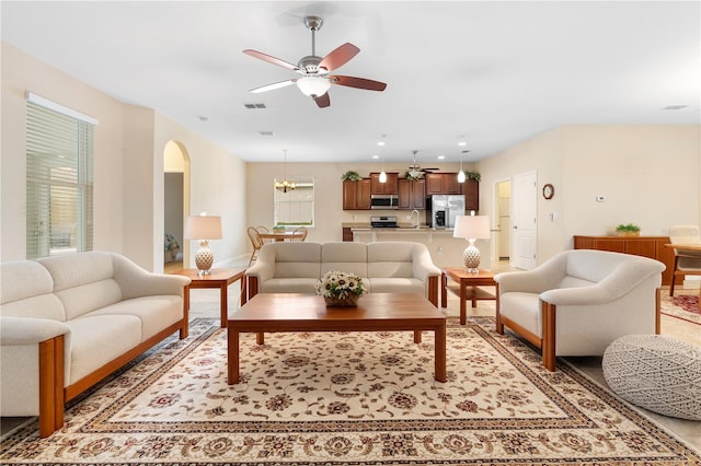 living room with ceiling fan with notable chandelier and sink