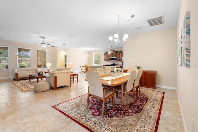 dining space featuring ceiling fan with notable chandelier