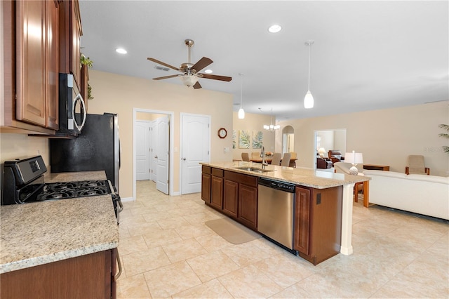 kitchen featuring light stone countertops, stainless steel appliances, a kitchen island with sink, sink, and pendant lighting