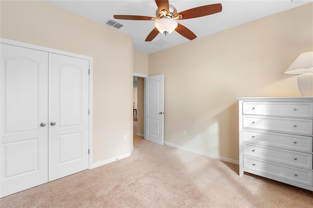 unfurnished bedroom featuring ceiling fan, light colored carpet, and a closet