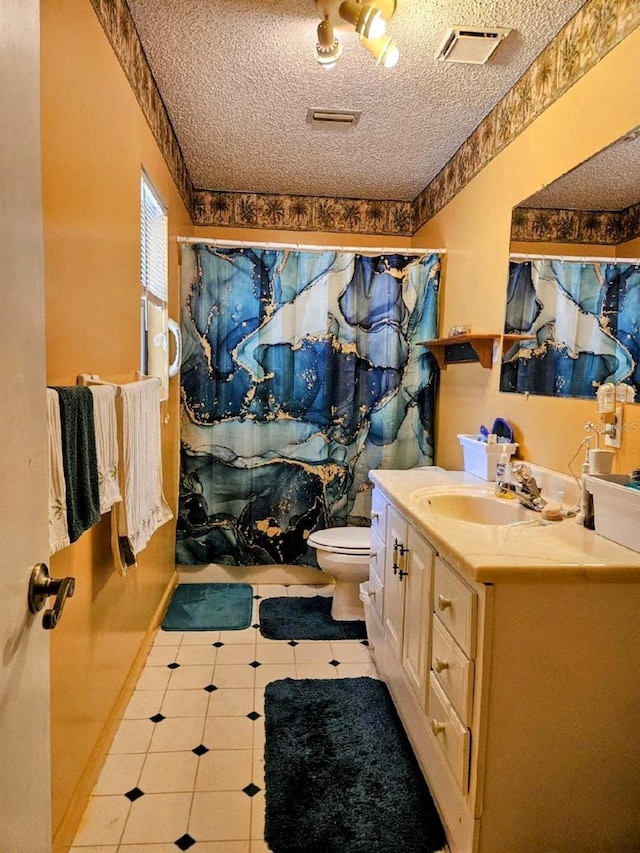 bathroom featuring walk in shower, tile patterned flooring, a textured ceiling, toilet, and vanity