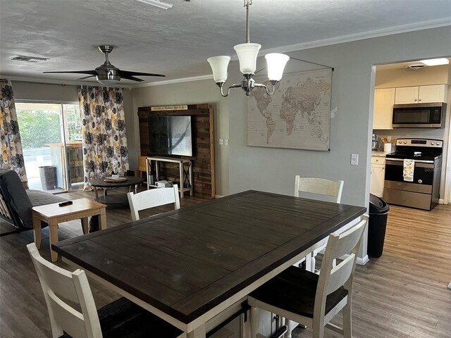 dining room featuring ceiling fan with notable chandelier, crown molding, and light wood-type flooring