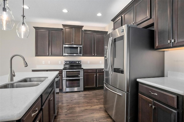 kitchen featuring dark brown cabinetry, dark hardwood / wood-style flooring, stainless steel appliances, sink, and hanging light fixtures