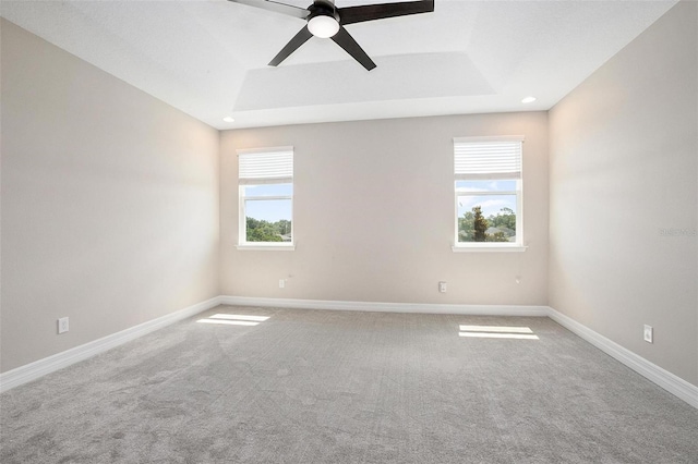 carpeted spare room featuring ceiling fan and a tray ceiling