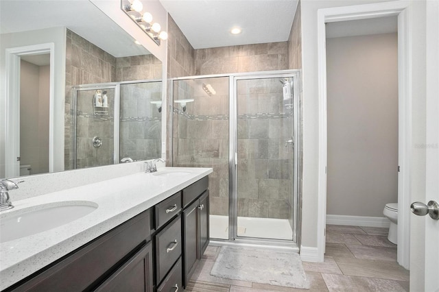 bathroom with toilet, tile patterned flooring, a shower with shower door, and vanity