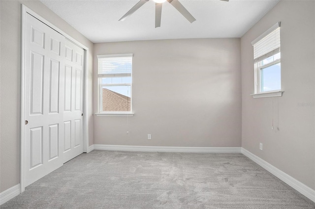 unfurnished bedroom featuring ceiling fan, light colored carpet, and a closet