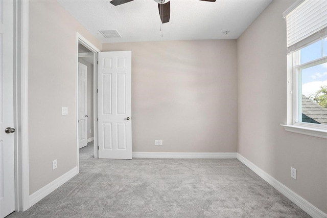 empty room featuring ceiling fan and light colored carpet