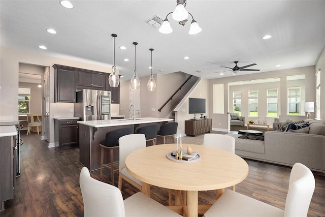 dining space with dark hardwood / wood-style floors, sink, and ceiling fan with notable chandelier