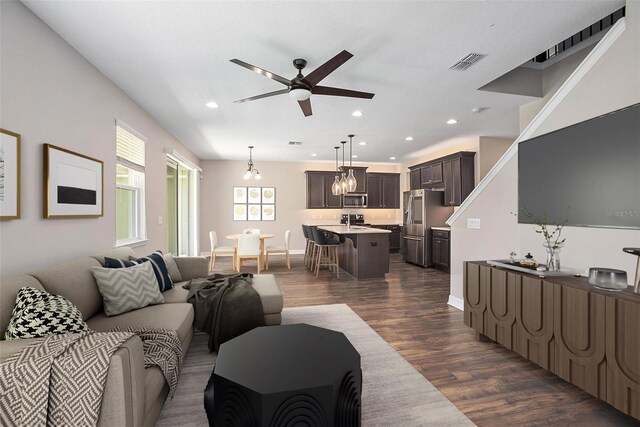 living room with ceiling fan with notable chandelier, sink, and dark hardwood / wood-style flooring