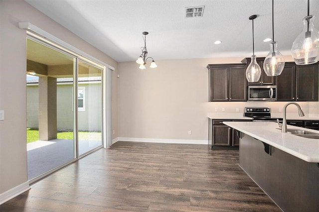 kitchen featuring dark wood-type flooring, stainless steel appliances, sink, hanging light fixtures, and a notable chandelier