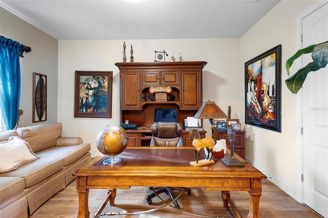 home office with light hardwood / wood-style floors and a textured ceiling