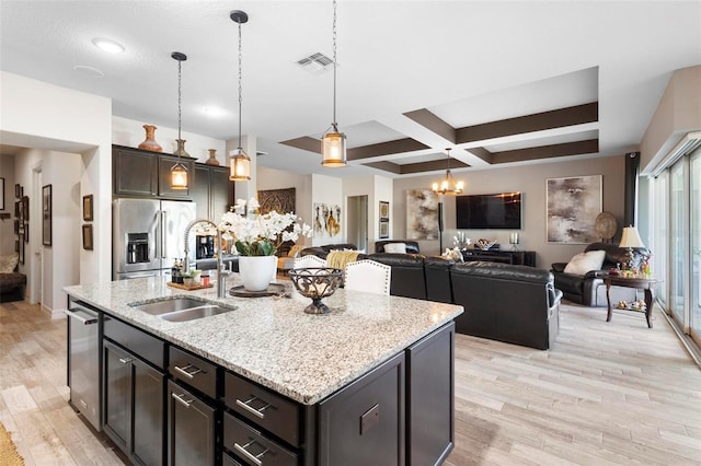 kitchen with stainless steel appliances, sink, decorative light fixtures, an inviting chandelier, and an island with sink