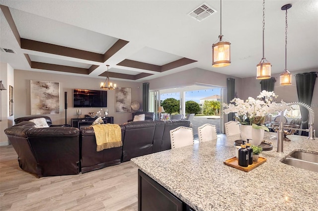 kitchen featuring light stone countertops, pendant lighting, a notable chandelier, and sink