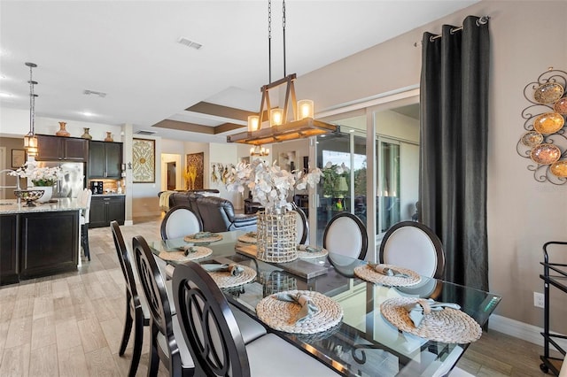 dining room featuring a chandelier, light hardwood / wood-style flooring, and beamed ceiling