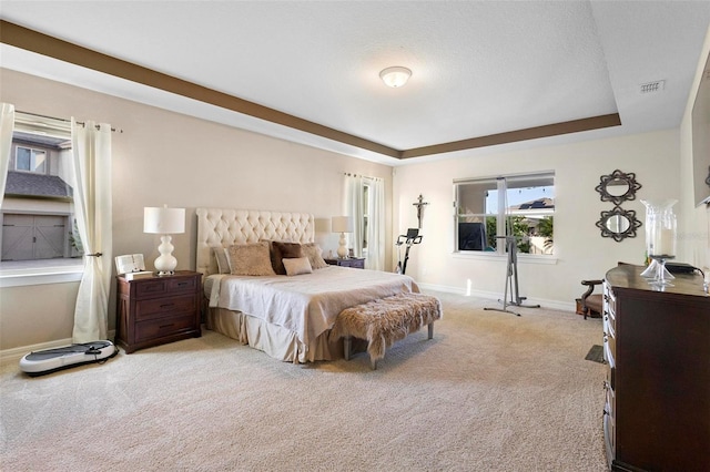 bedroom with a tray ceiling and light colored carpet