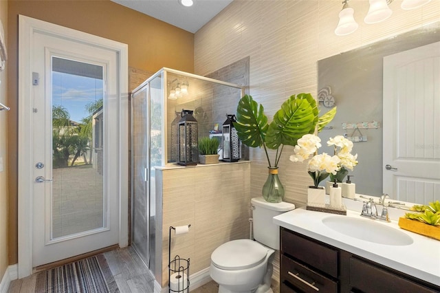 bathroom with hardwood / wood-style flooring, vanity, toilet, and a shower with shower door