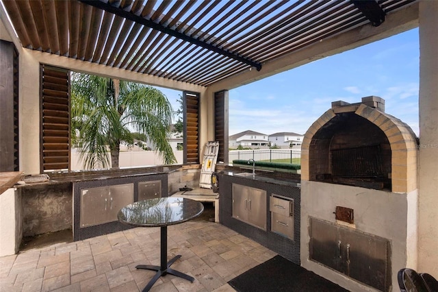 view of patio featuring an outdoor kitchen, a pergola, and sink