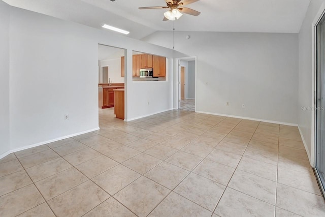 unfurnished living room with ceiling fan, light tile patterned floors, and vaulted ceiling