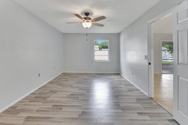 empty room featuring ceiling fan, light hardwood / wood-style flooring, and a textured ceiling