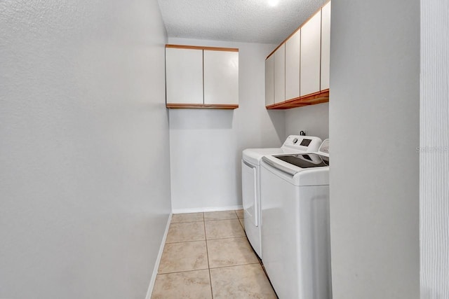 laundry room with light tile patterned floors, cabinets, a textured ceiling, and independent washer and dryer