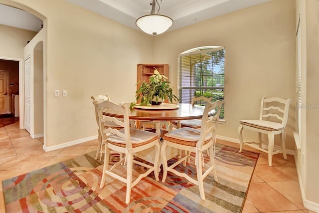 dining area featuring light tile flooring and a raised ceiling