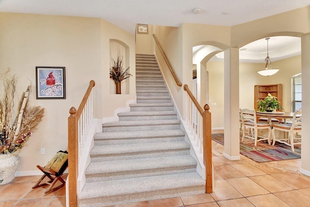 stairs with a tray ceiling and tile floors