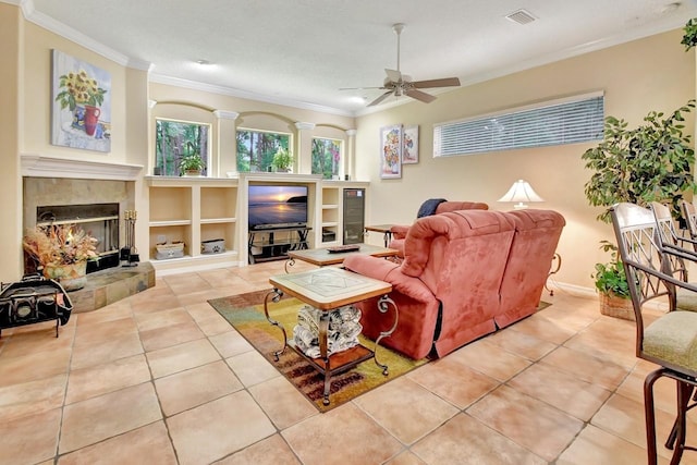 living room featuring tile floors, a tiled fireplace, ceiling fan, and built in features