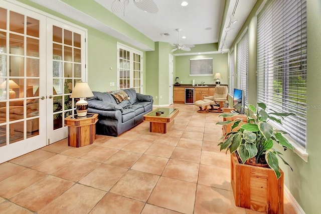 tiled living room with beverage cooler, ceiling fan, and french doors