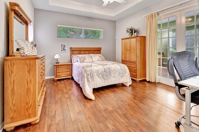 bedroom with ceiling fan, a raised ceiling, and wood-type flooring