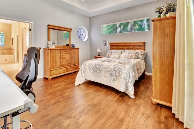 bedroom with ensuite bathroom, multiple windows, and hardwood / wood-style floors