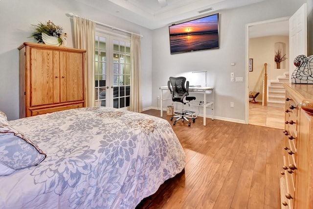 bedroom featuring a raised ceiling, ceiling fan, french doors, and hardwood / wood-style flooring