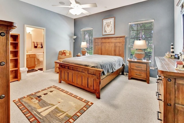 bedroom with ceiling fan, light carpet, and ensuite bathroom