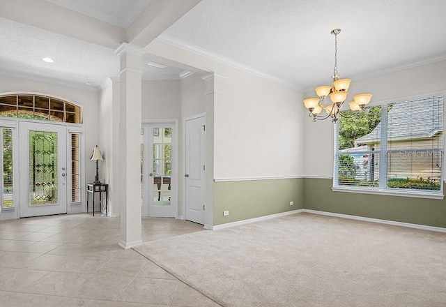 carpeted entryway featuring decorative columns, crown molding, plenty of natural light, and an inviting chandelier