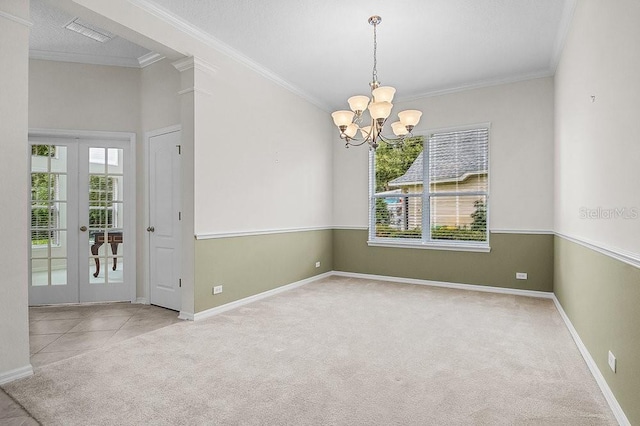 spare room with a chandelier, french doors, light carpet, and crown molding