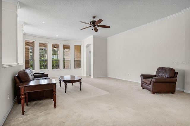 living area featuring light carpet, a textured ceiling, ceiling fan, and crown molding