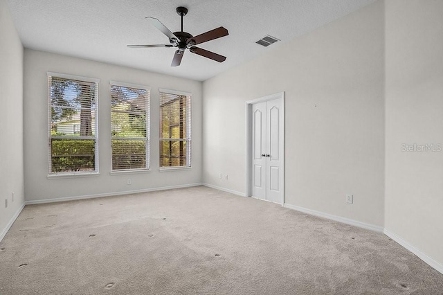 carpeted spare room with ceiling fan and a textured ceiling