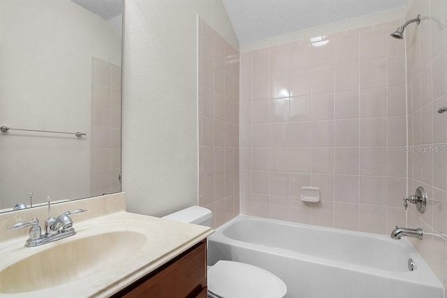 full bathroom with tiled shower / bath, vanity, a textured ceiling, and toilet