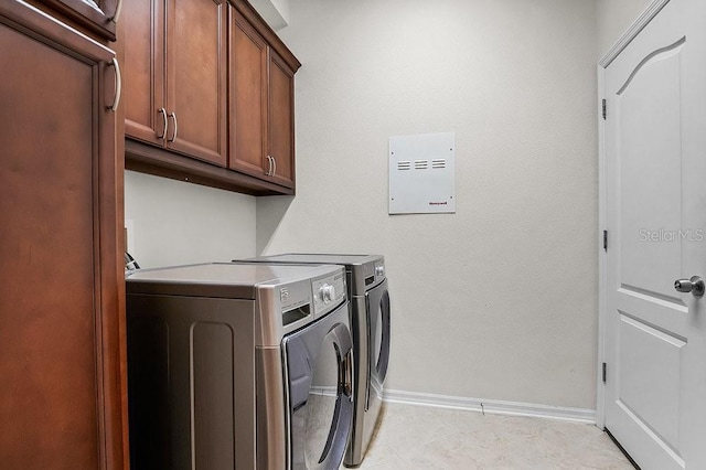 clothes washing area with washer and clothes dryer and cabinets