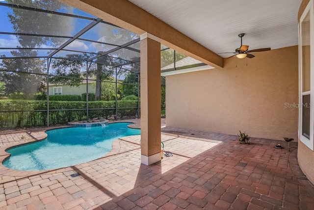 view of pool with a patio area, ceiling fan, and glass enclosure