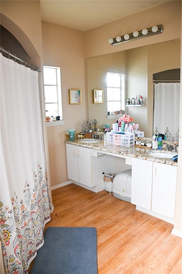 bathroom with a healthy amount of sunlight, dual bowl vanity, and hardwood / wood-style flooring