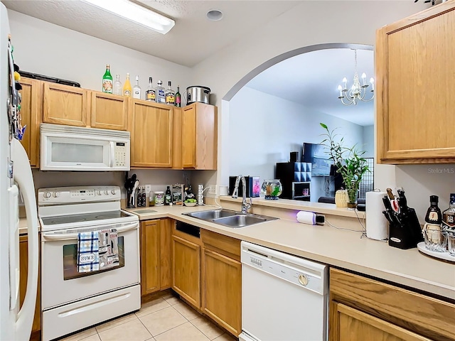 kitchen featuring white appliances, hanging light fixtures, sink, light tile patterned floors, and a chandelier