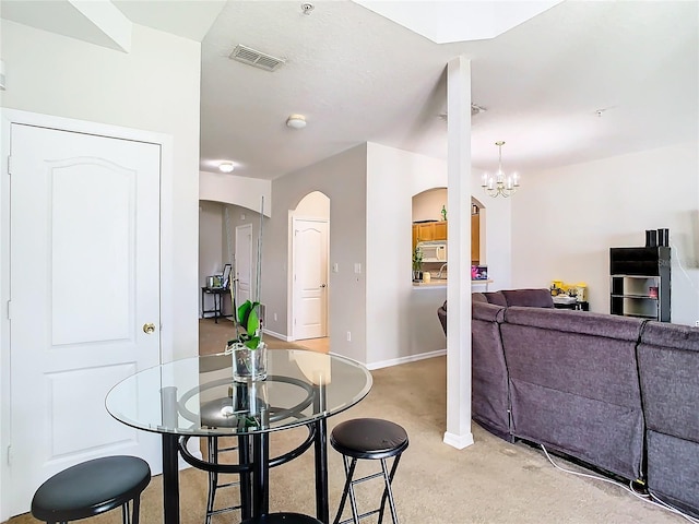 dining space with a notable chandelier and light colored carpet