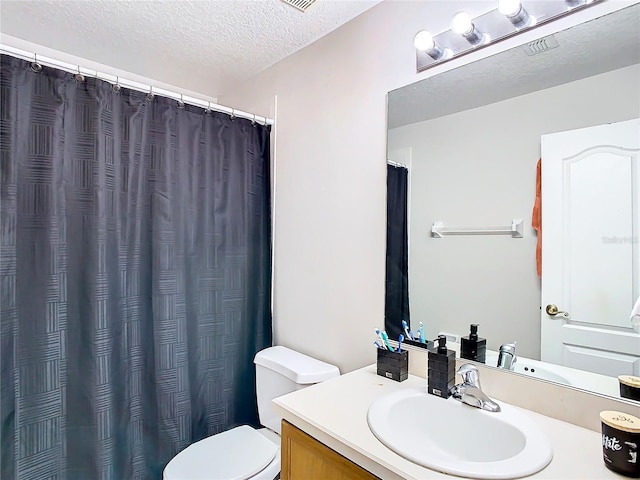 bathroom with vanity, toilet, and a textured ceiling