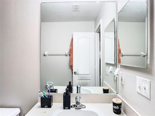 bathroom featuring sink, a textured ceiling, and toilet