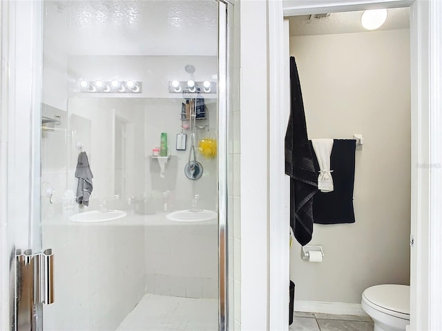 bathroom featuring tile patterned flooring, toilet, and a shower with door