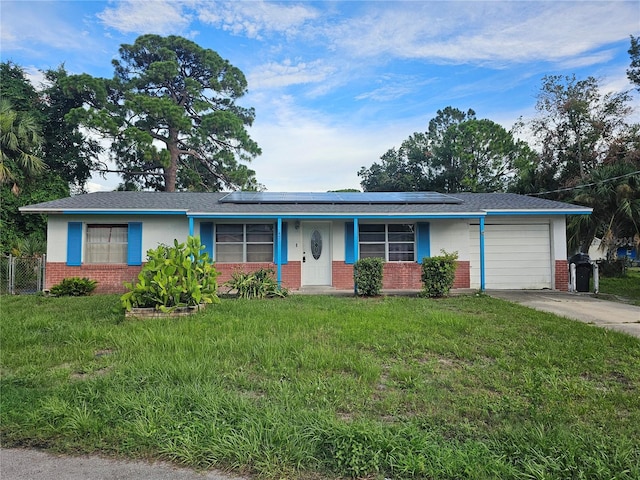 ranch-style house with a garage, a front yard, and solar panels