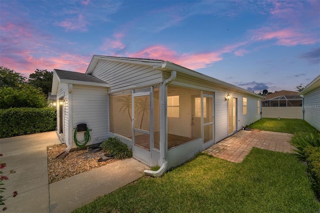 property exterior at dusk featuring a sunroom and a yard