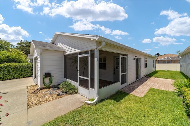 rear view of property featuring a lawn and a sunroom