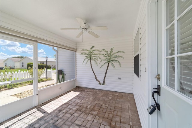 unfurnished sunroom featuring ceiling fan