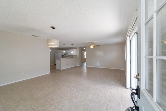 unfurnished living room with ceiling fan, light tile patterned floors, and a textured ceiling